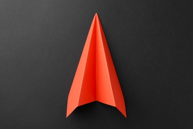 Photo of One handmade orange paper plane on grey background, top view