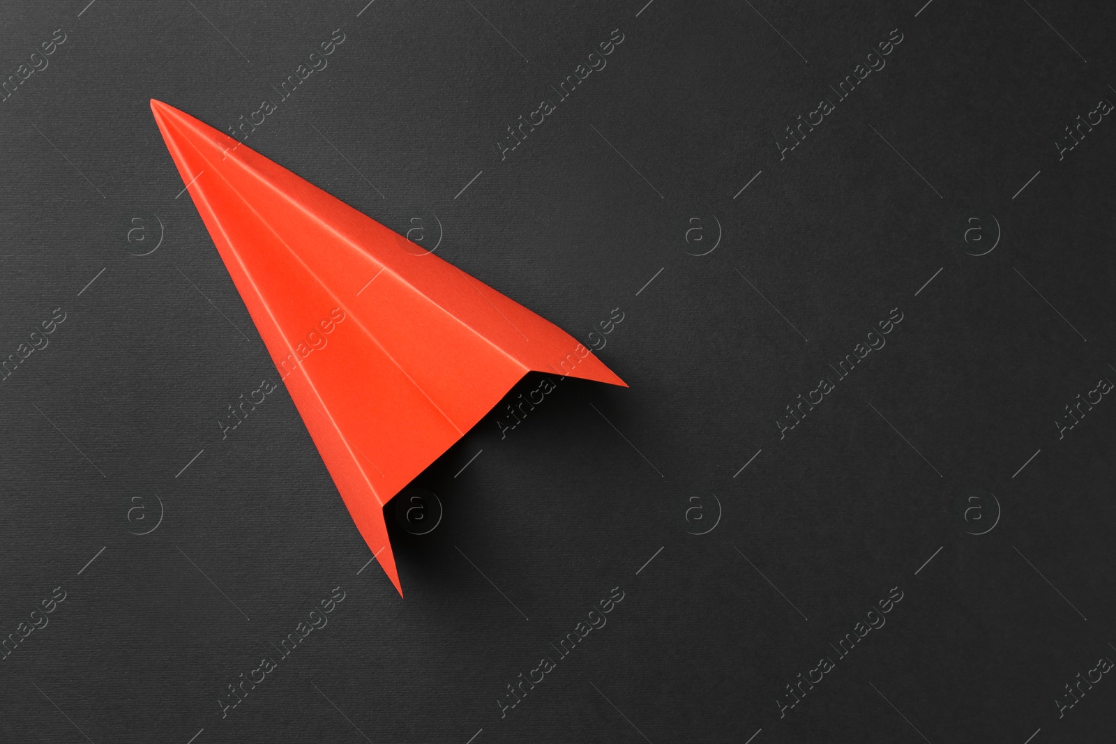 Photo of One handmade orange paper plane on grey background, top view. Space for text