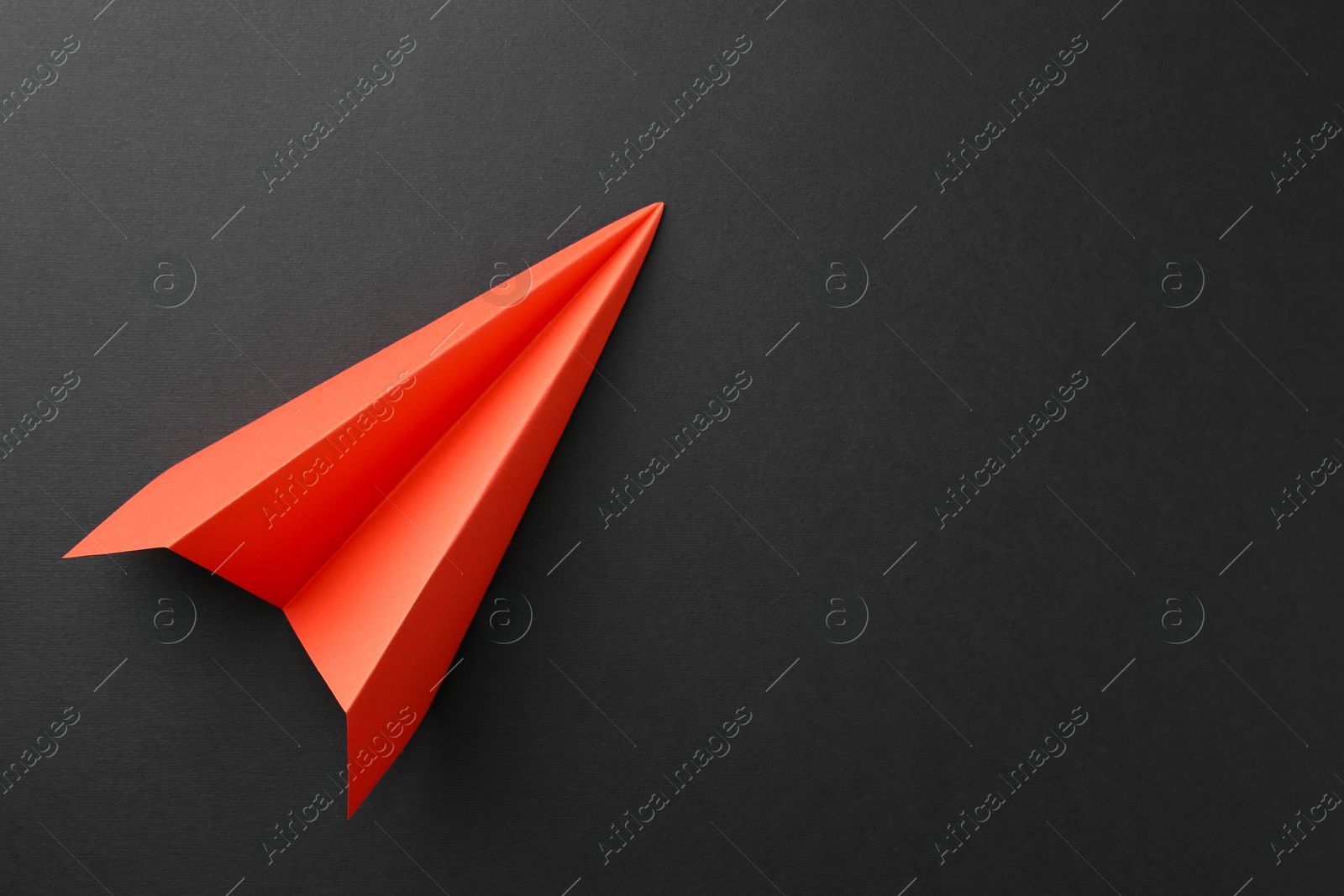 Photo of One handmade orange paper plane on grey background, top view. Space for text