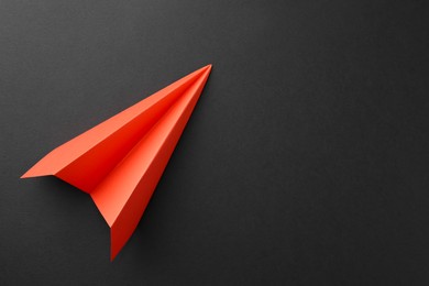 Photo of One handmade orange paper plane on grey background, top view. Space for text