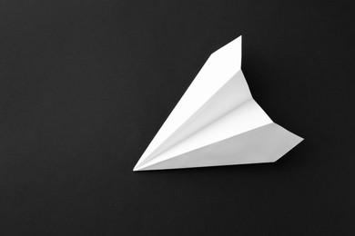 Photo of One handmade paper plane on black background, top view. Space for text