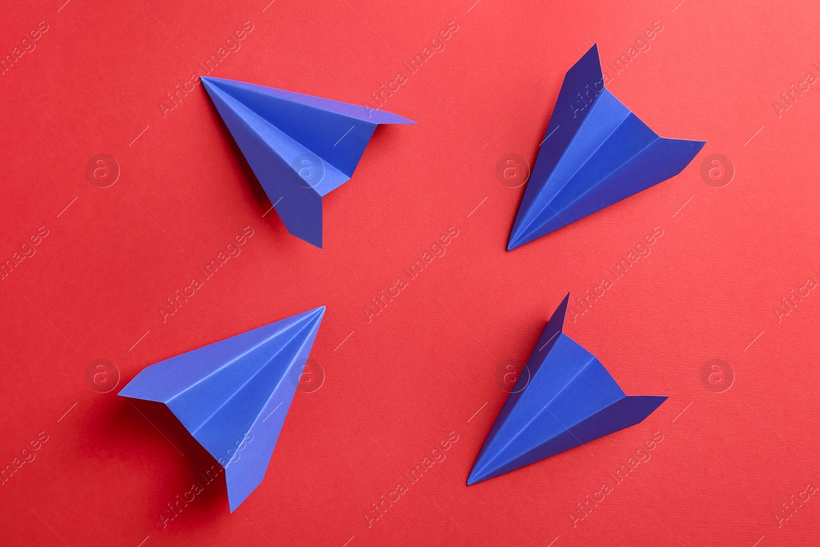 Photo of Blue paper planes on red background, top view