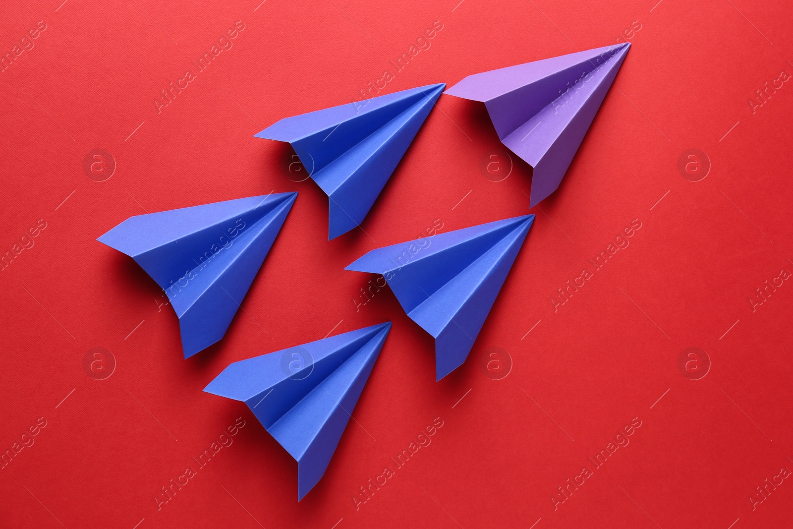 Photo of Colorful paper planes on red background, top view