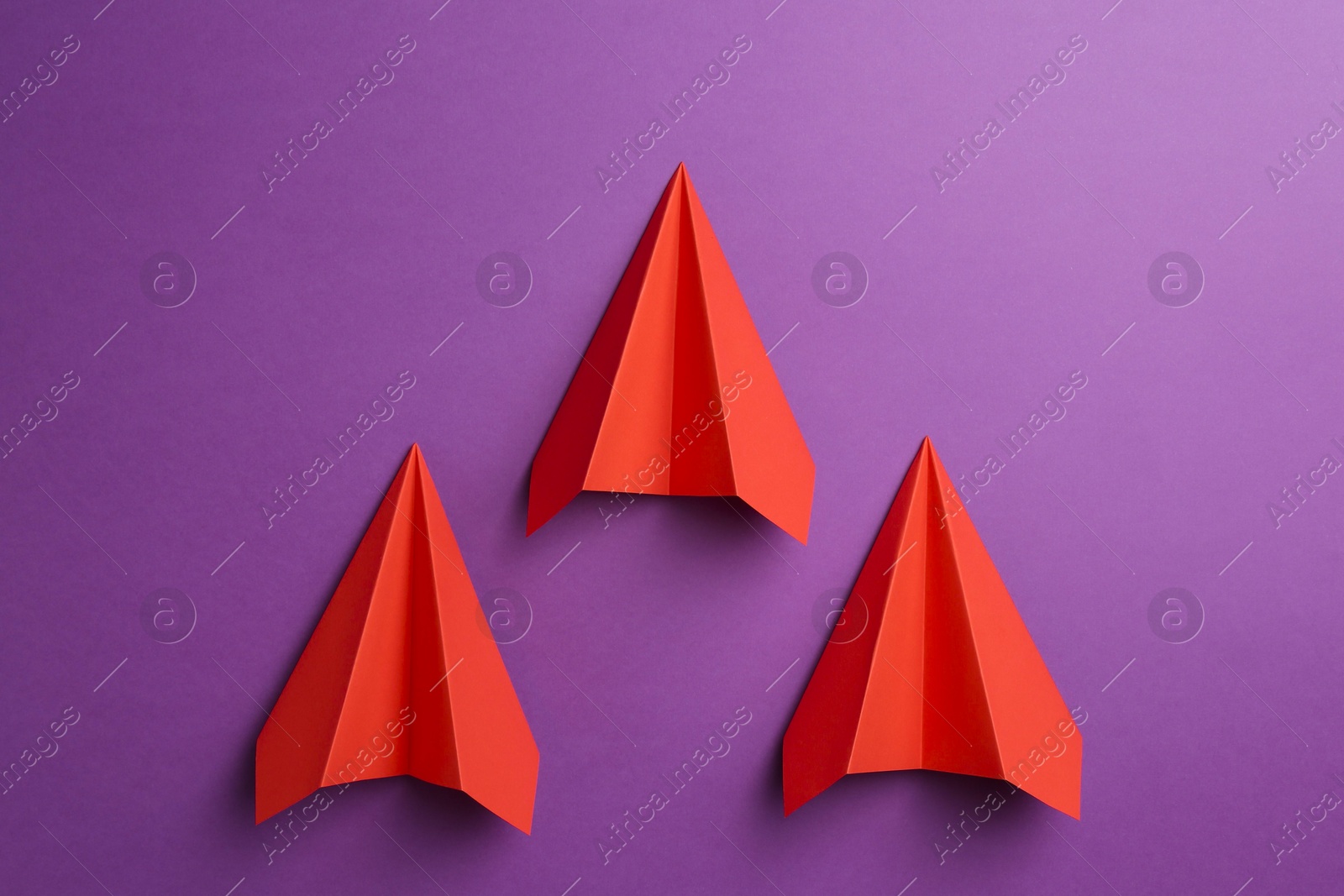 Photo of Red paper planes on purple background, top view