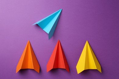 Photo of Colorful paper planes on purple background, top view