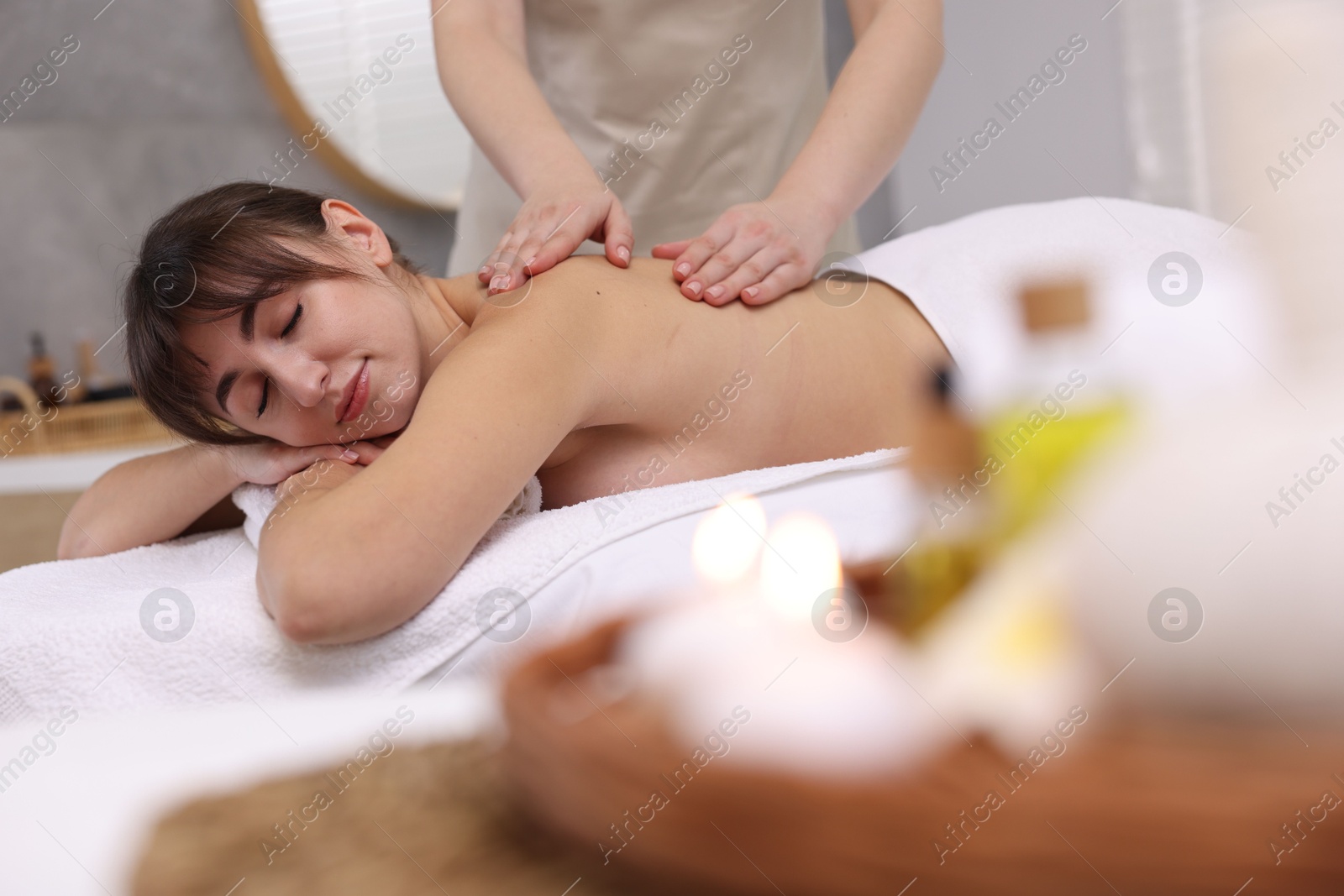 Photo of Young woman receiving back massage in spa salon