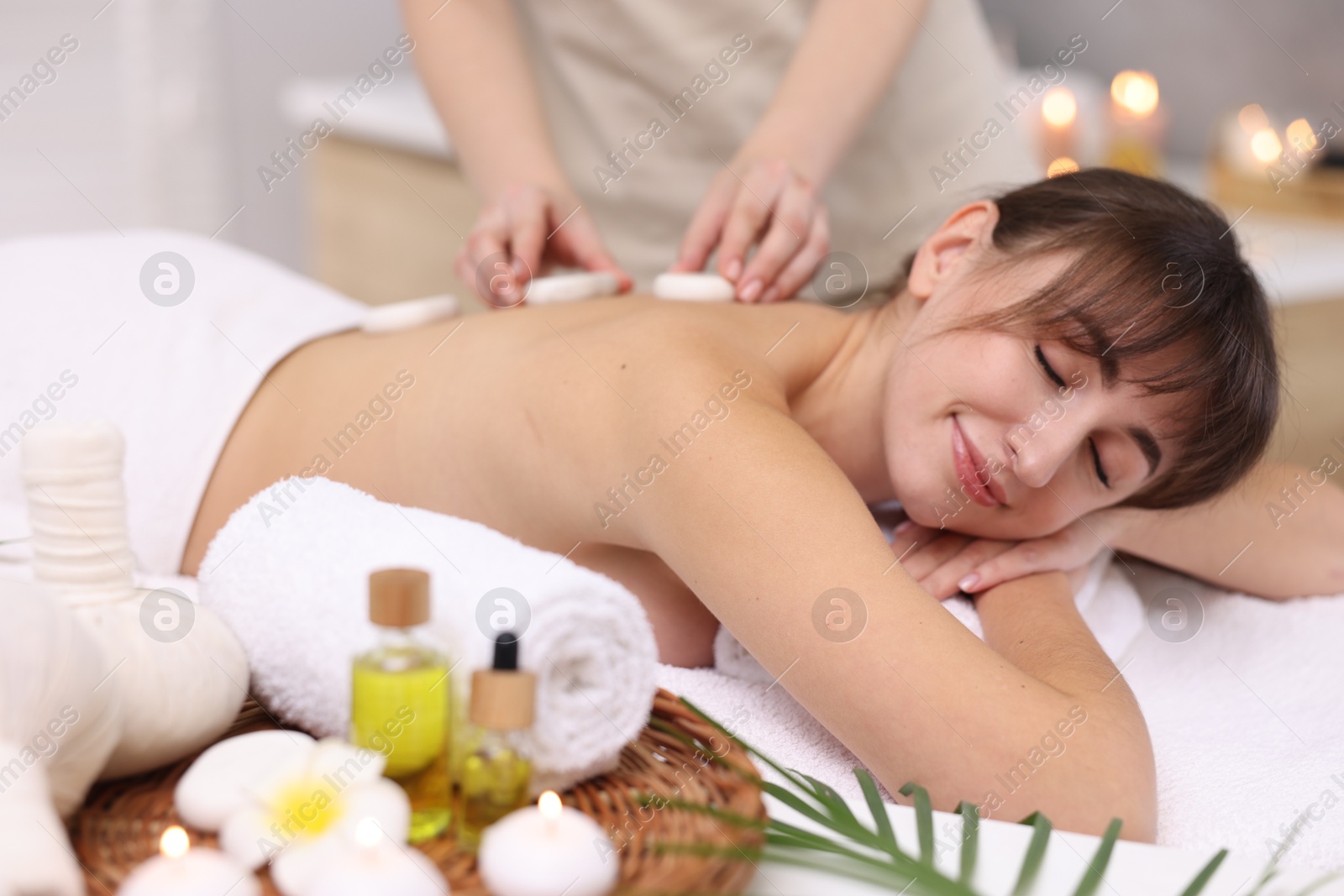 Photo of Young woman receiving hot stone massage in spa salon