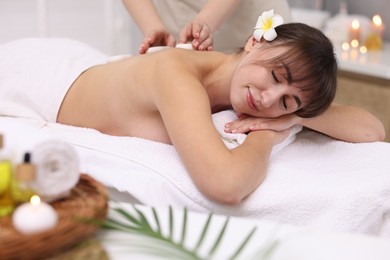 Photo of Young woman receiving hot stone massage in spa salon