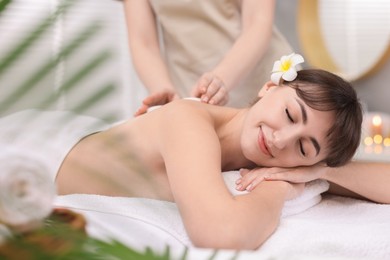 Photo of Young woman receiving hot stone massage in spa salon