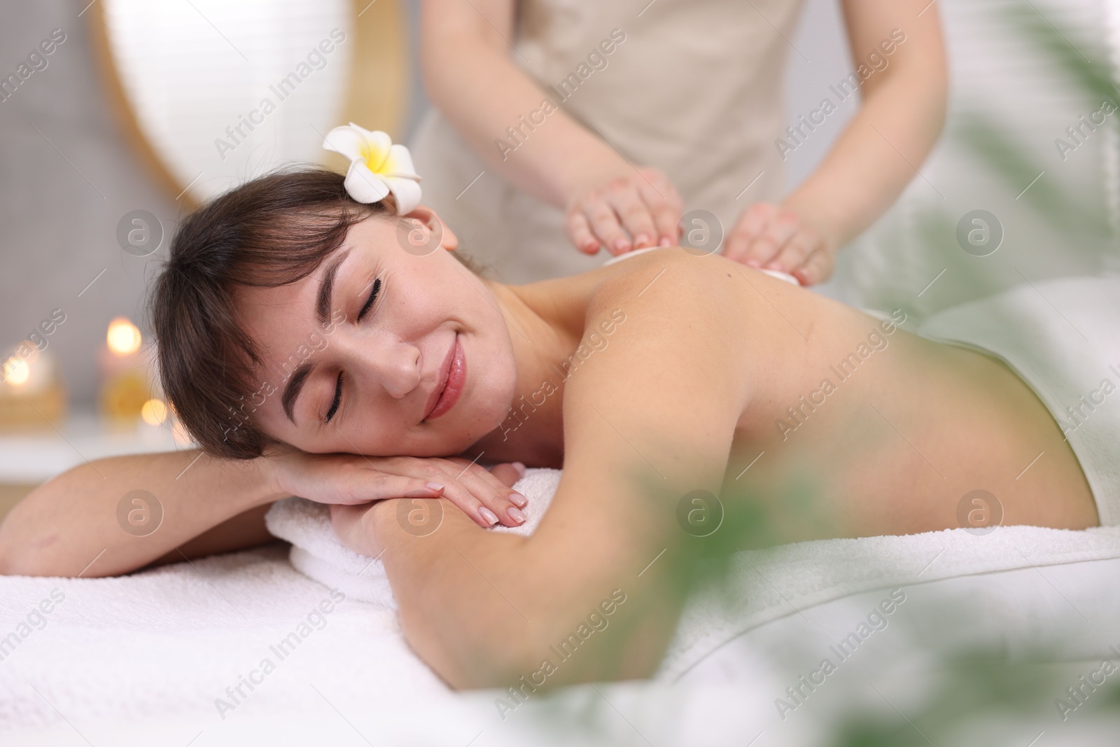 Photo of Young woman receiving hot stone massage in spa salon