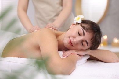 Photo of Young woman receiving hot stone massage in spa salon