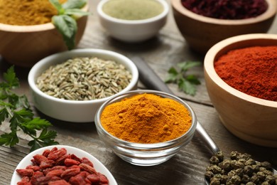 Photo of Different aromatic spices on wooden table, closeup