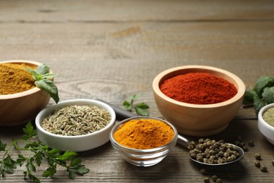 Photo of Different aromatic spices on wooden table, closeup. Space for text