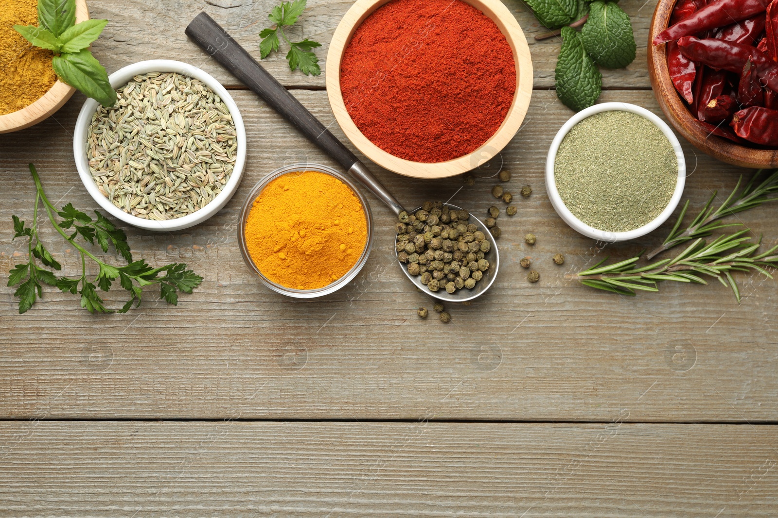 Photo of Different aromatic spices on wooden table, flat lay. Space for text