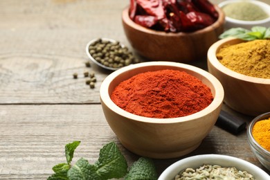 Photo of Different aromatic spices on wooden table, closeup. Space for text