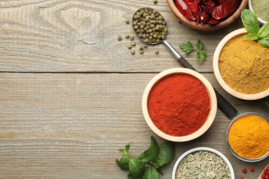 Photo of Different aromatic spices on wooden table, flat lay. Space for text