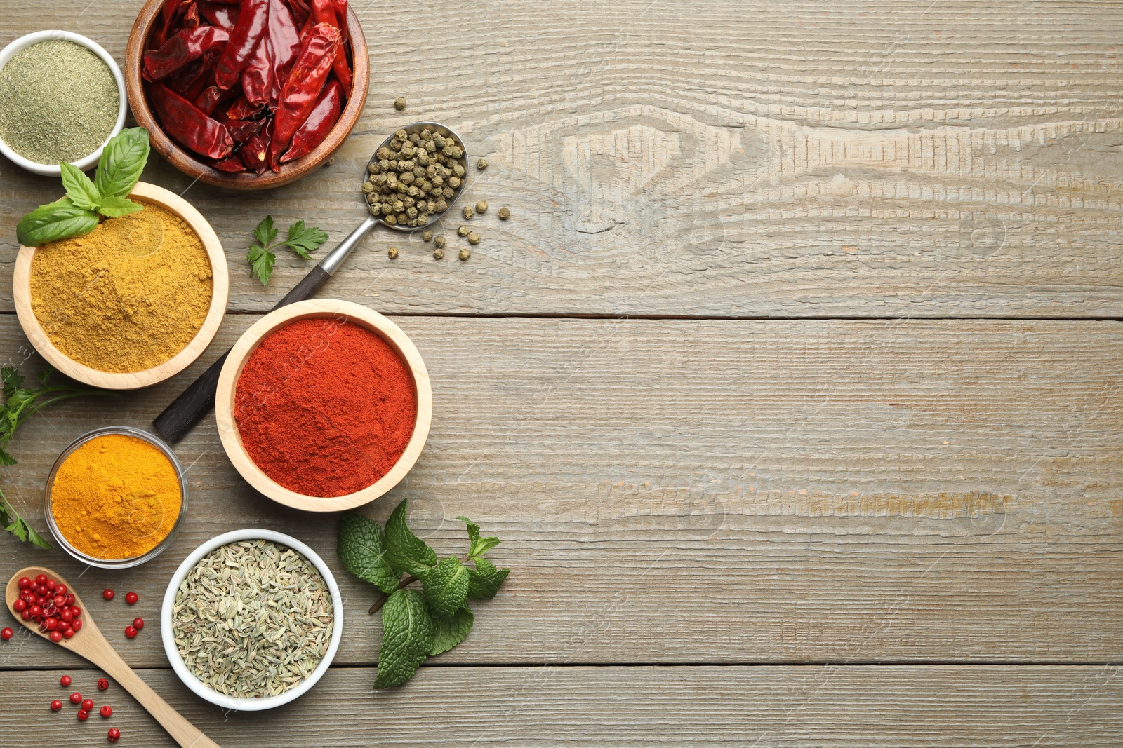 Photo of Different aromatic spices on wooden table, flat lay. Space for text