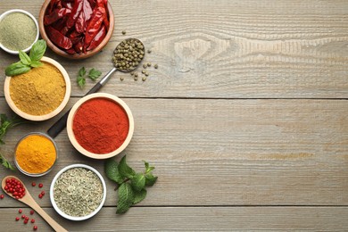 Photo of Different aromatic spices on wooden table, flat lay. Space for text