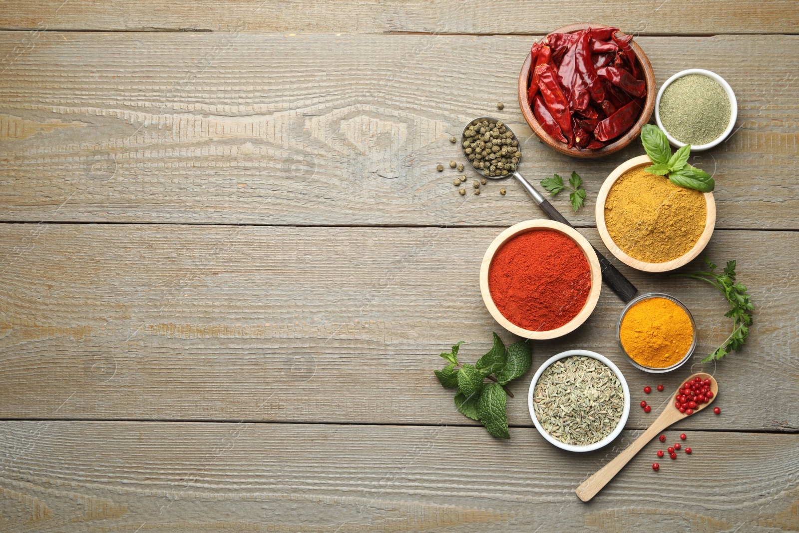 Photo of Different aromatic spices on wooden table, flat lay. Space for text