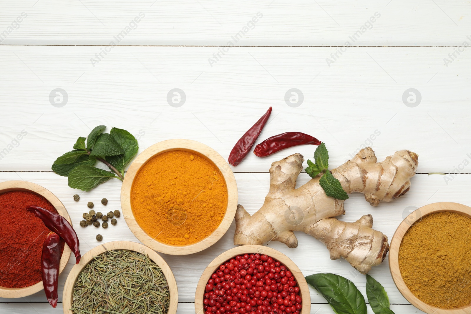 Photo of Different aromatic spices on white wooden table, flat lay. Space for text