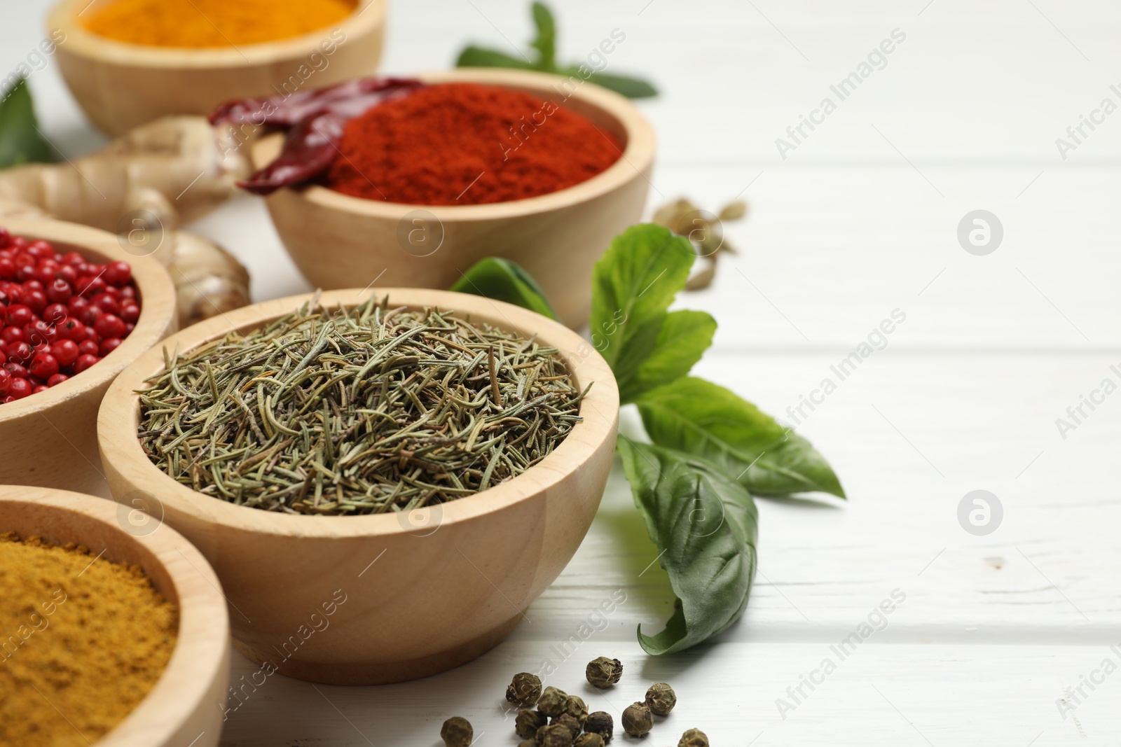 Photo of Different aromatic spices on white wooden table, closeup