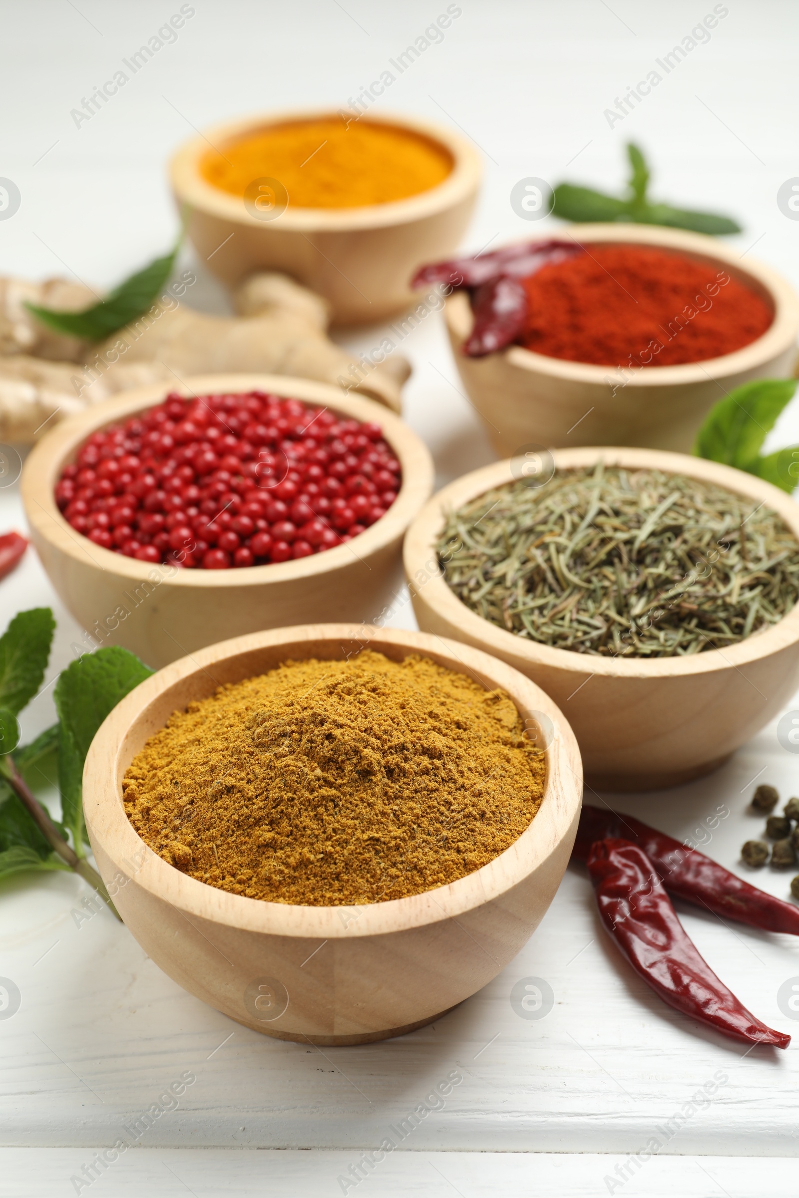 Photo of Different aromatic spices on white wooden table, closeup