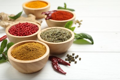 Different aromatic spices on white wooden table, closeup