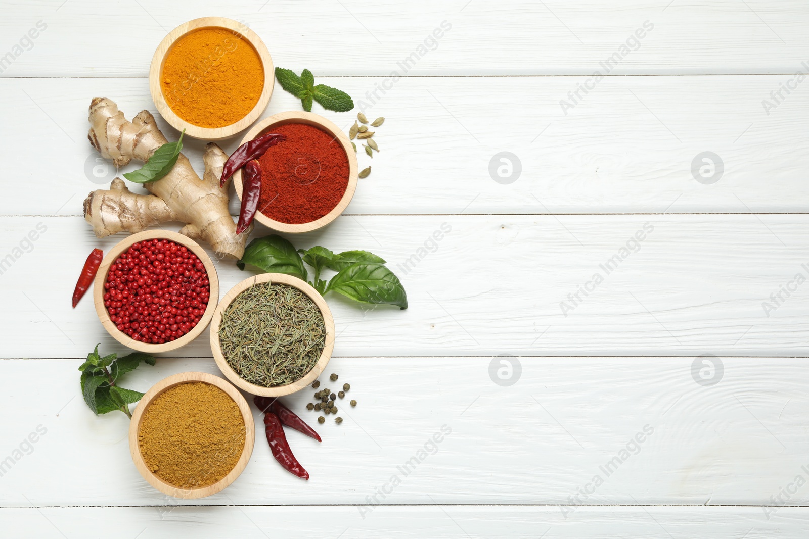 Photo of Different aromatic spices on white wooden table, flat lay. Space for text