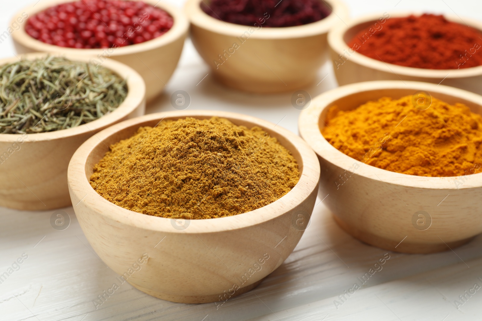 Photo of Different aromatic spices on white wooden table, closeup