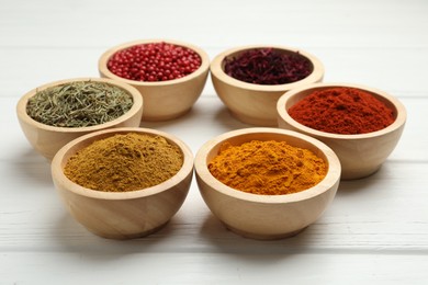 Different aromatic spices on white wooden table, closeup