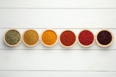 Different aromatic spices on white wooden table, flat lay