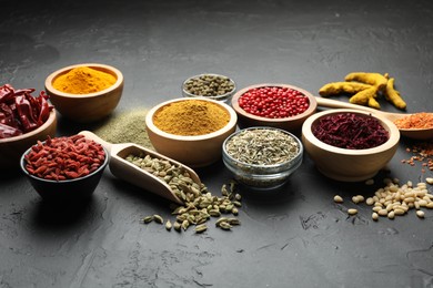 Different aromatic spices in bowls on black table