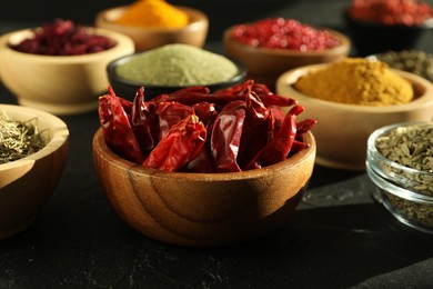 Photo of Different aromatic spices on black table, closeup