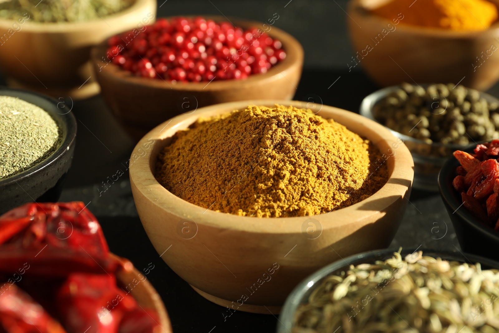 Photo of Different aromatic spices on black table, closeup