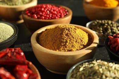 Different aromatic spices on black table, closeup