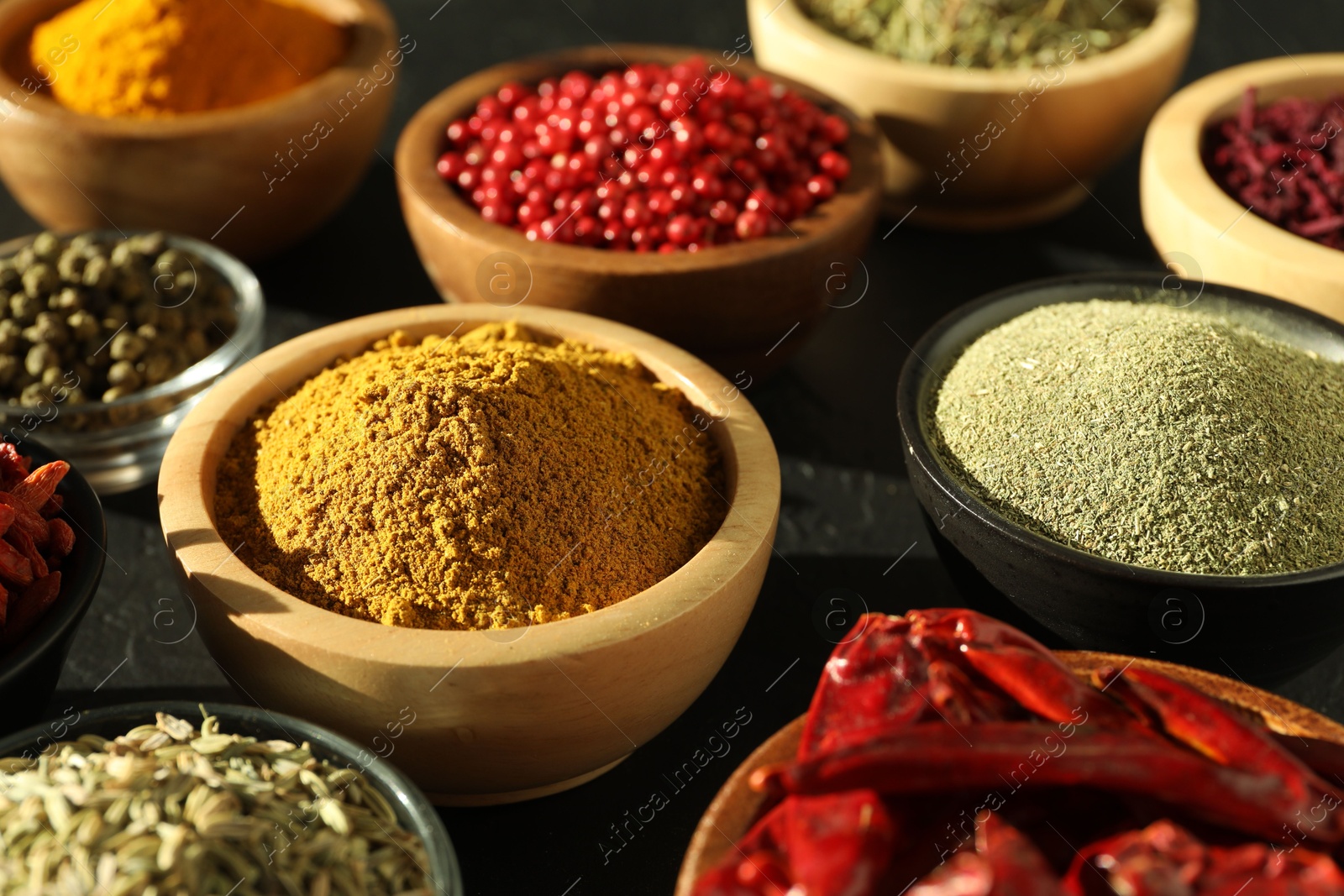 Photo of Different aromatic spices on black table, closeup