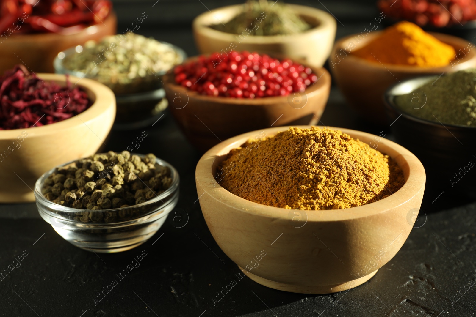 Photo of Different aromatic spices on black table, closeup