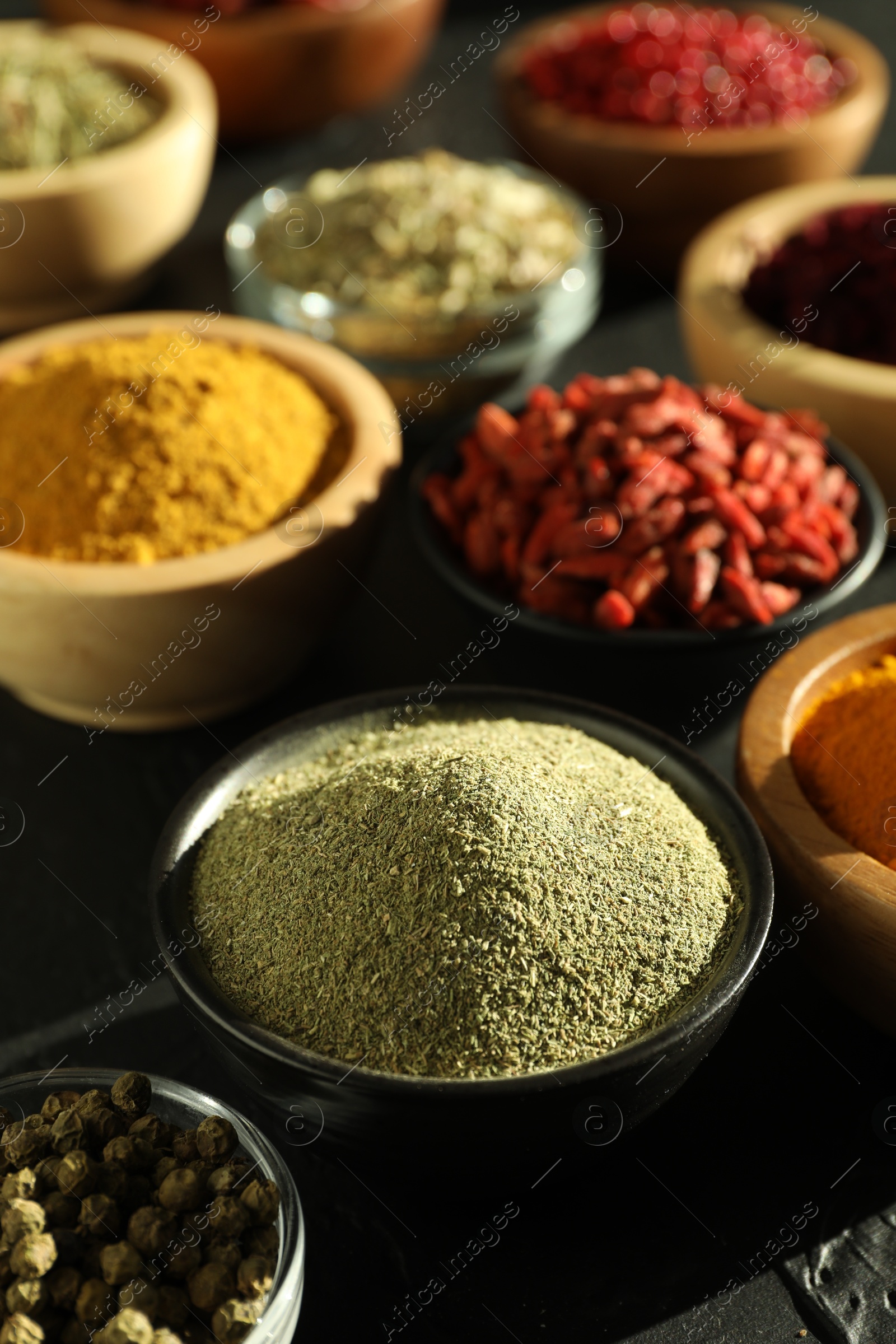 Photo of Different aromatic spices on black table, closeup