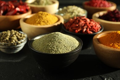 Photo of Different aromatic spices on black table, closeup