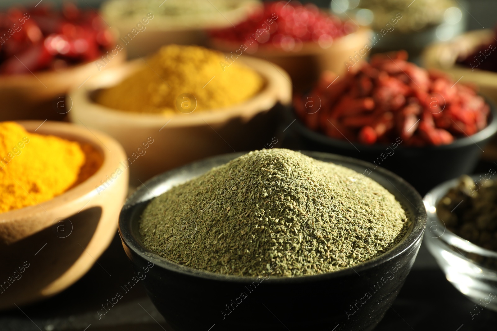 Photo of Different aromatic spices on black table, closeup