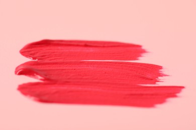 Photo of Sample of pink lip gloss on beige background, closeup