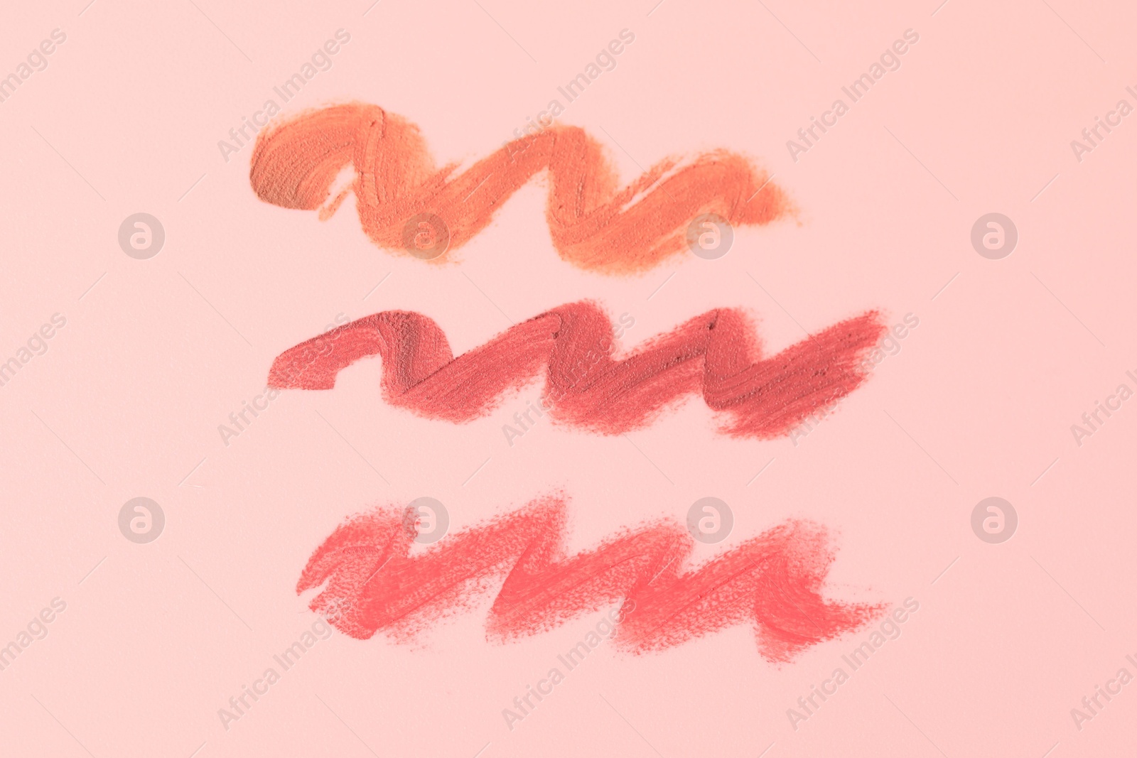 Photo of Samples of bright lipsticks on beige background, top view