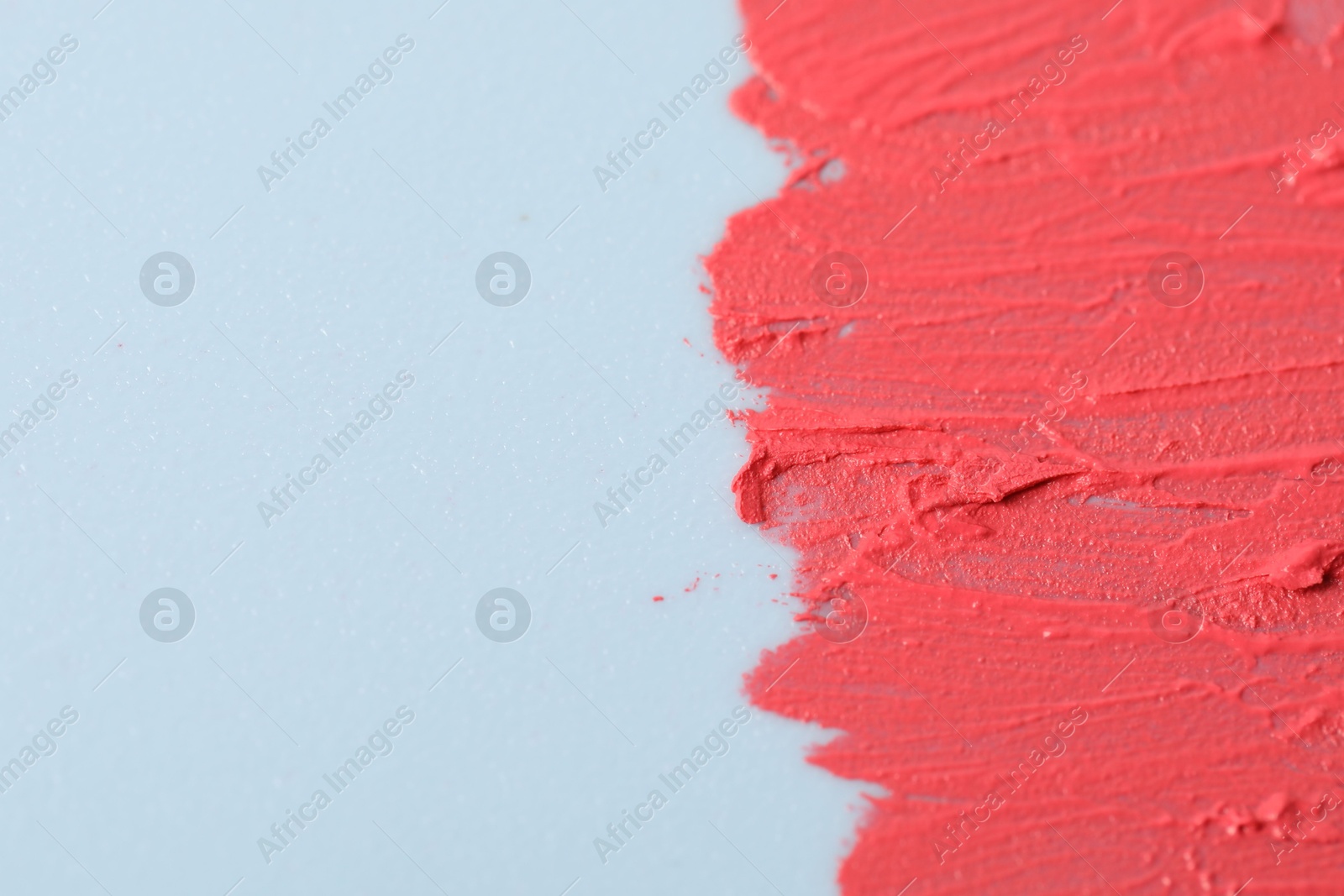 Photo of Sample of pink lipstick on light blue background, closeup. Space for text