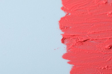 Photo of Sample of pink lipstick on light blue background, closeup. Space for text