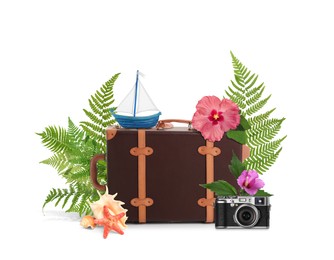 Image of Leather travel suitcase, toy sailboat, seashells, sea star, camera, tropical leaves and flowers on white background