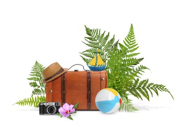 Image of Brown travel suitcase, hat, camera, toy sailboat, beach ball, tropical leaves and flower on white background