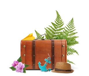 Brown travel suitcase, paper plane, toy anchor, hat, tropical leaves and flowers on white background