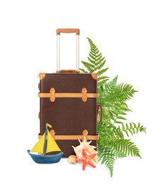 Brown travel suitcase, tropical leaves, sea star, seashells and toy sailboat on white background