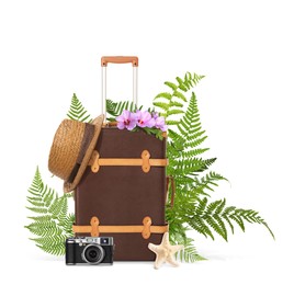 Brown travel suitcase, hat, camera, sea star, tropical leaves and flowers on white background