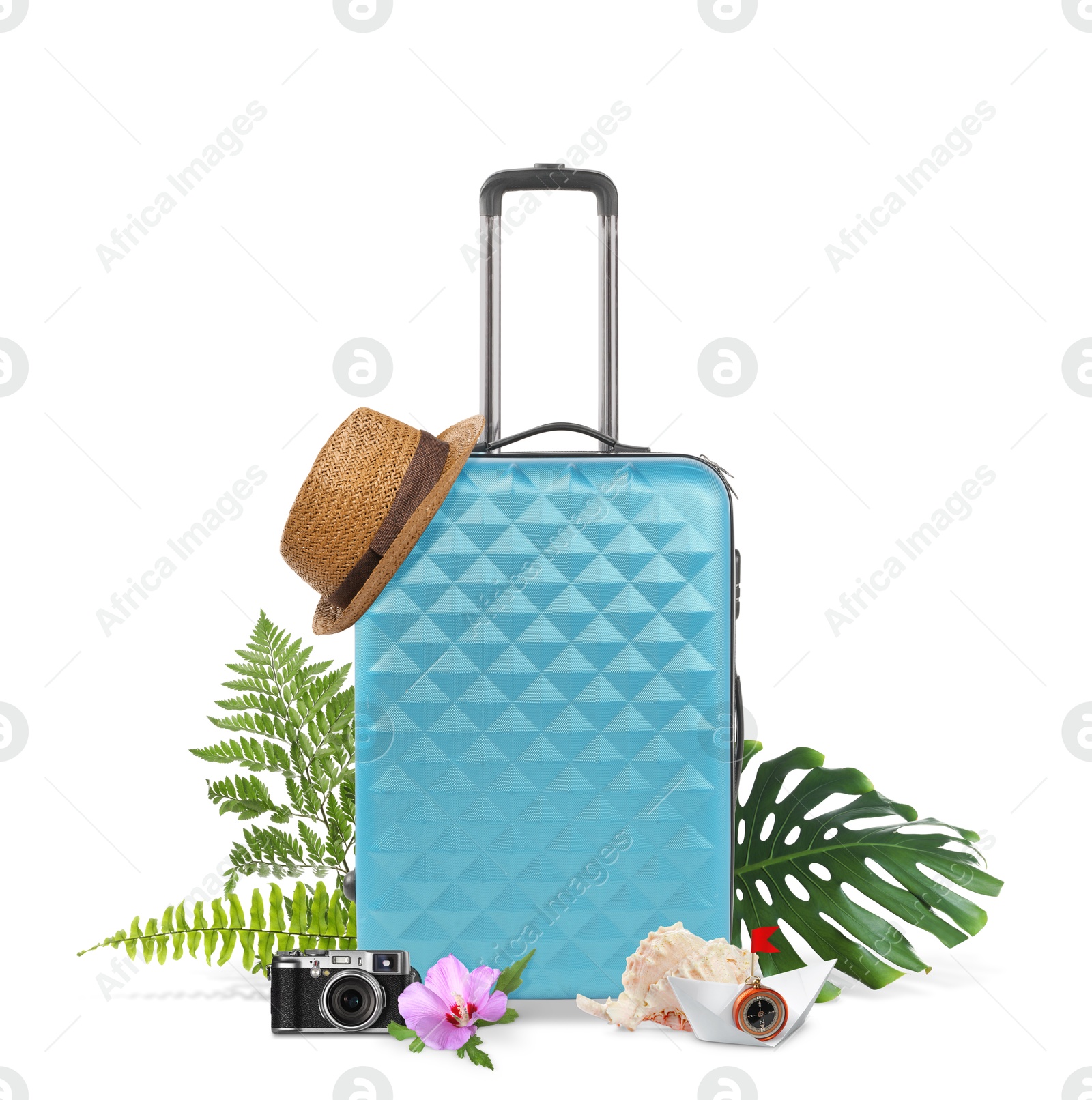 Image of Light blue travel suitcase, hat, camera, seashell, paper boat, tropical leaves and flower on white background